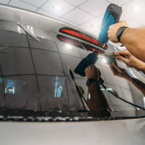 Car window tinting. Process of Installation window tint in Car Detailing Studio Garage by professional detailer.